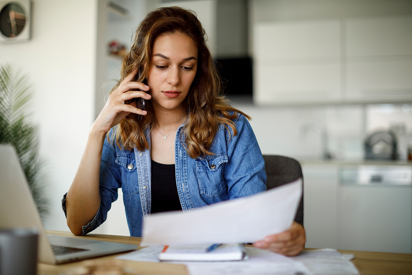 A woman talks on the phone while looking at paperwork