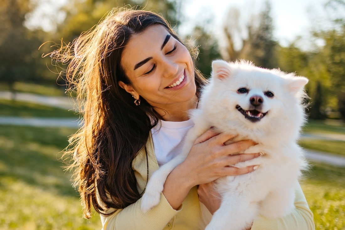 A woman looks adoringly at the small white dog in her arms