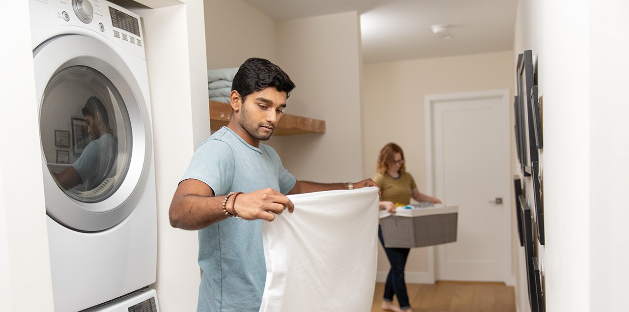 A man folding laundry in his home's laundry room. emergency kit