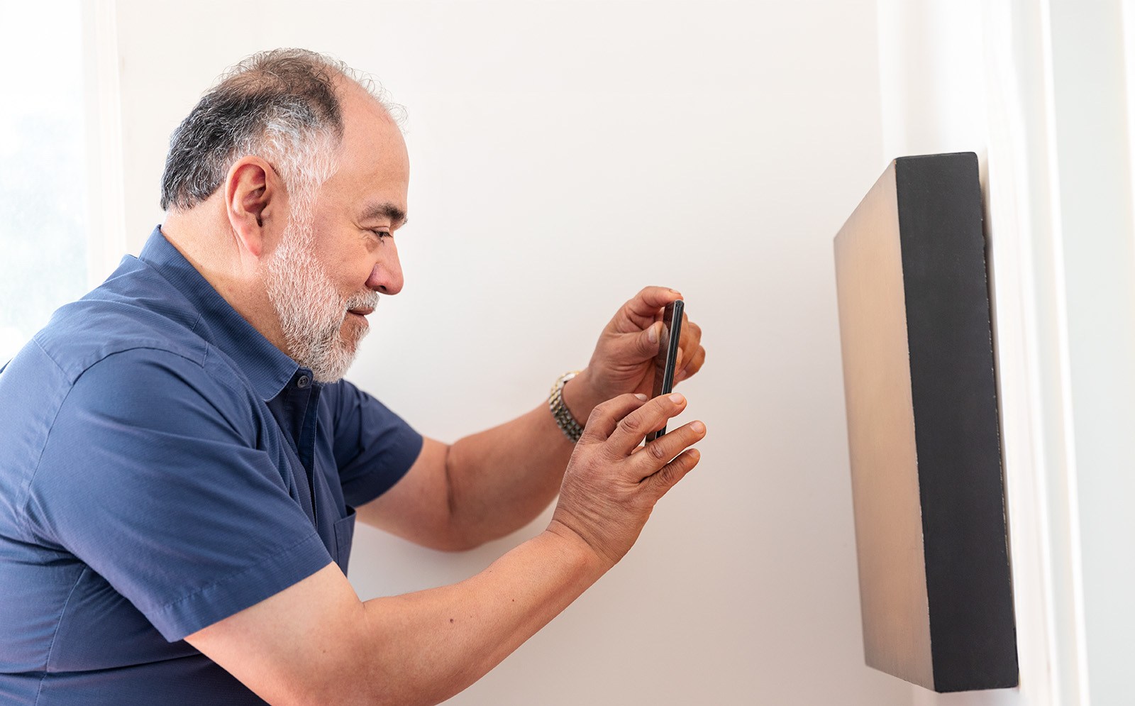 A man takes a photo of a painting to create a home inventory
