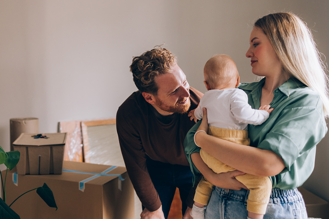 A young couple with a baby surrounded by moving boxes as they move into a new home. renters insurance